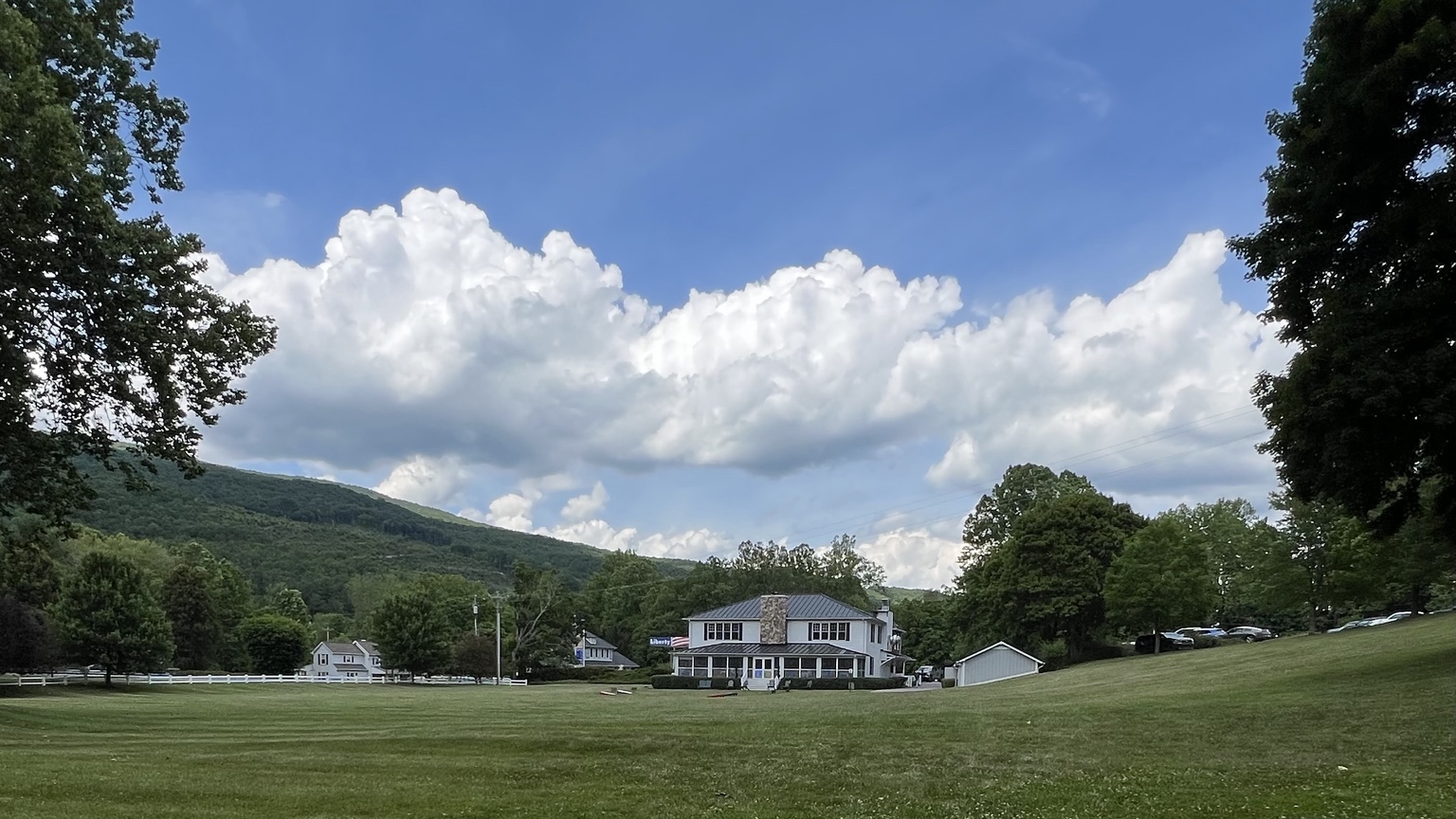 The Paint Bank property under a broad summer sky, with mountains and clapboard buildings across a grassy lawn