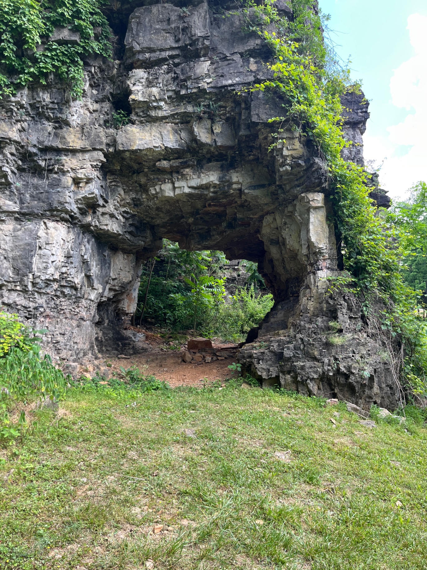 Natural stone arch formation in the limestone chimneys with green vegetation framing the opening