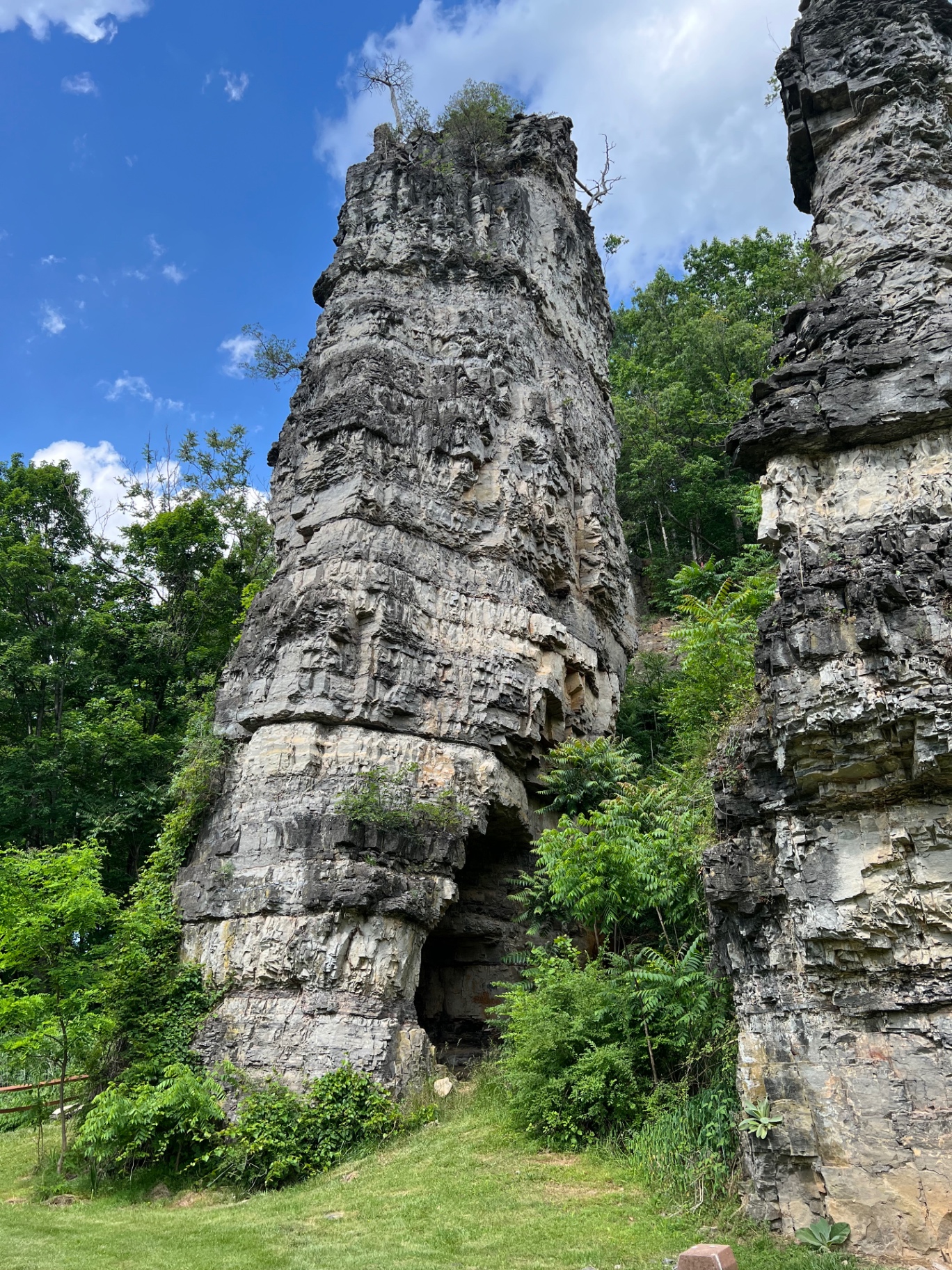 Close-up of a massive limestone pillar with a small cave opening at the base