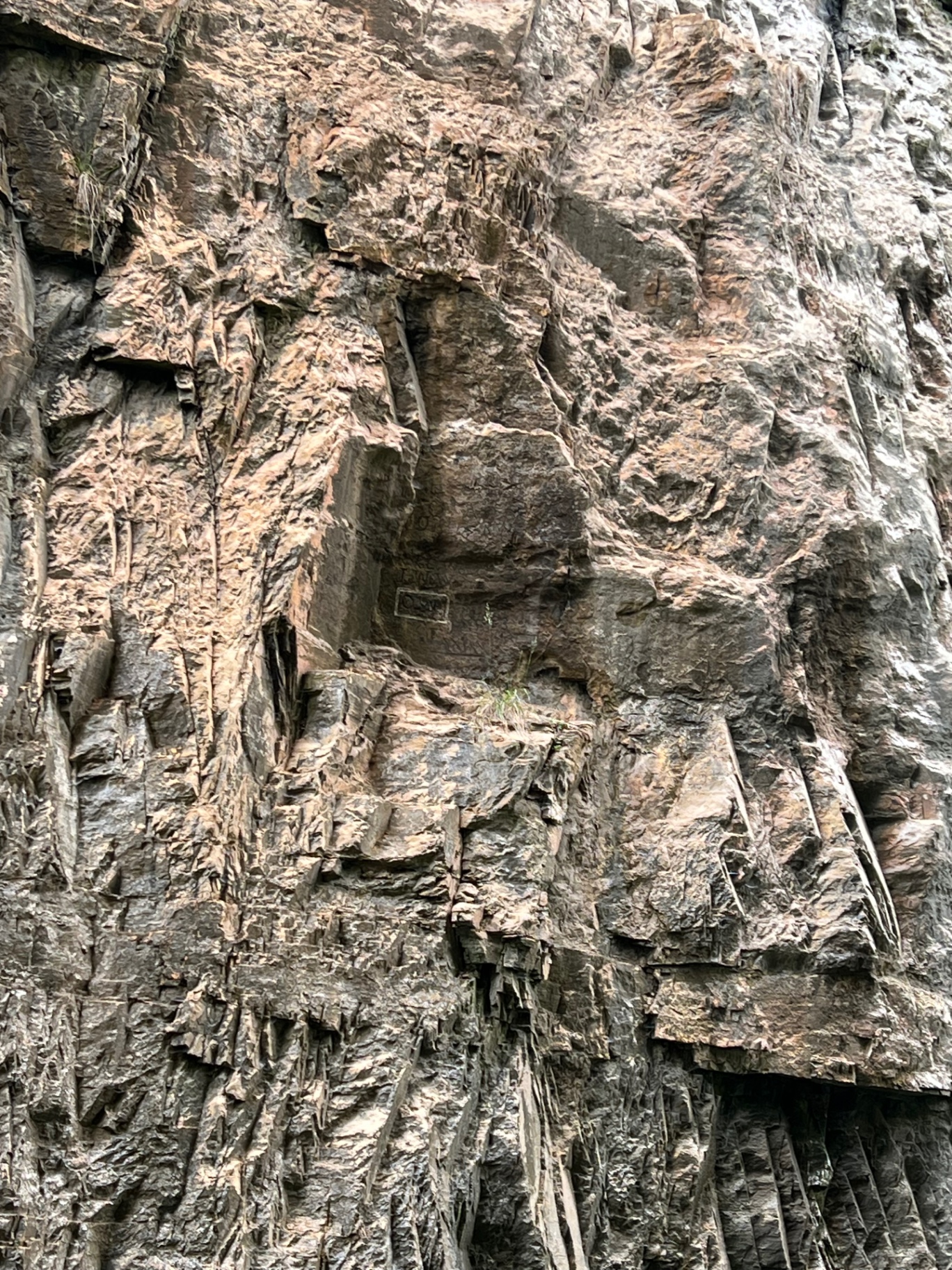 Weathered limestone cliff face with faint historical carvings visible in the rock
