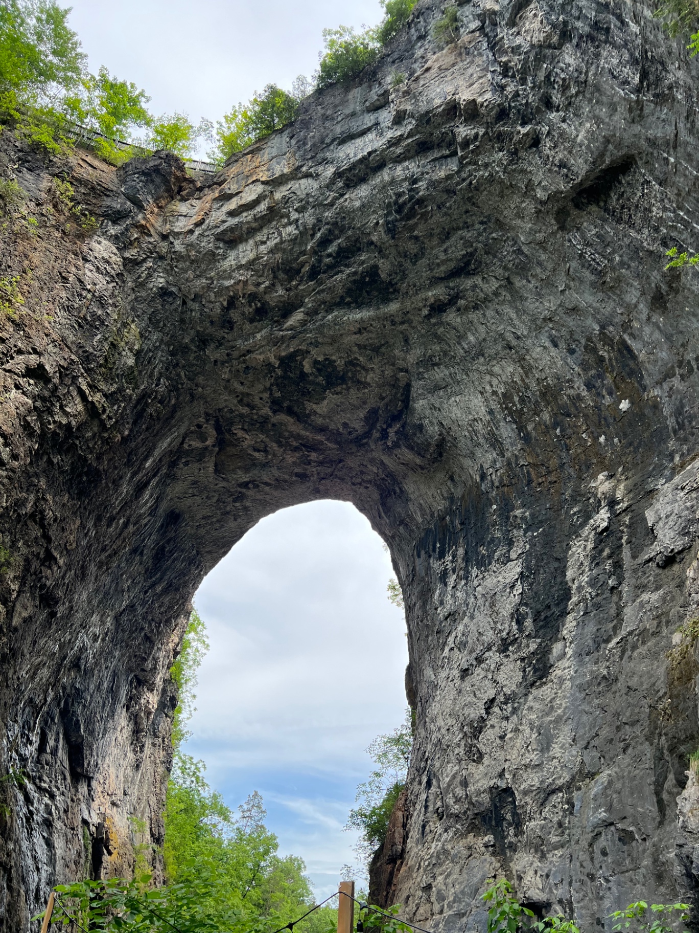 Backlit view through the arch of Natural Bridge, blue sky framed by the limestone opening